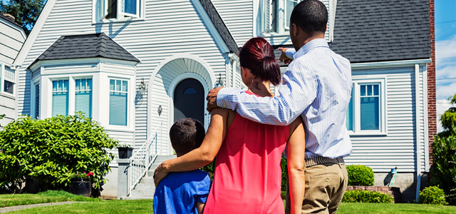 Family standing in front of a house and gazing at it